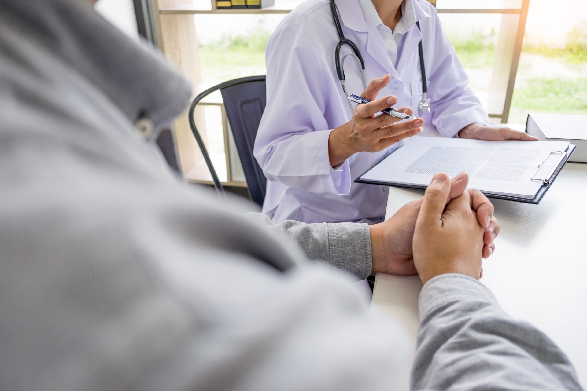 Midsection Of Doctor And Patient Talking In Office